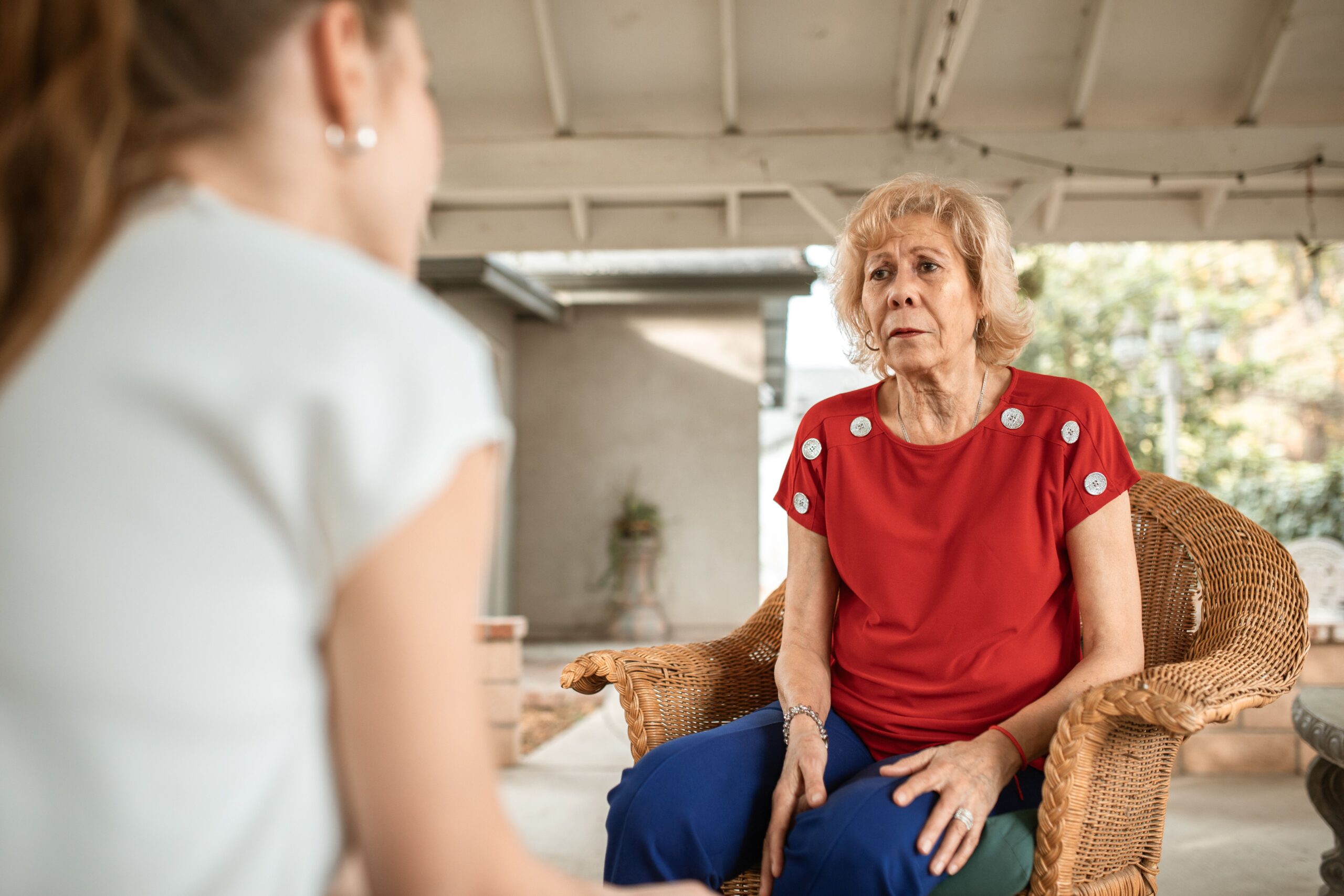 A caregiver visiting and talking with a senior woman at home