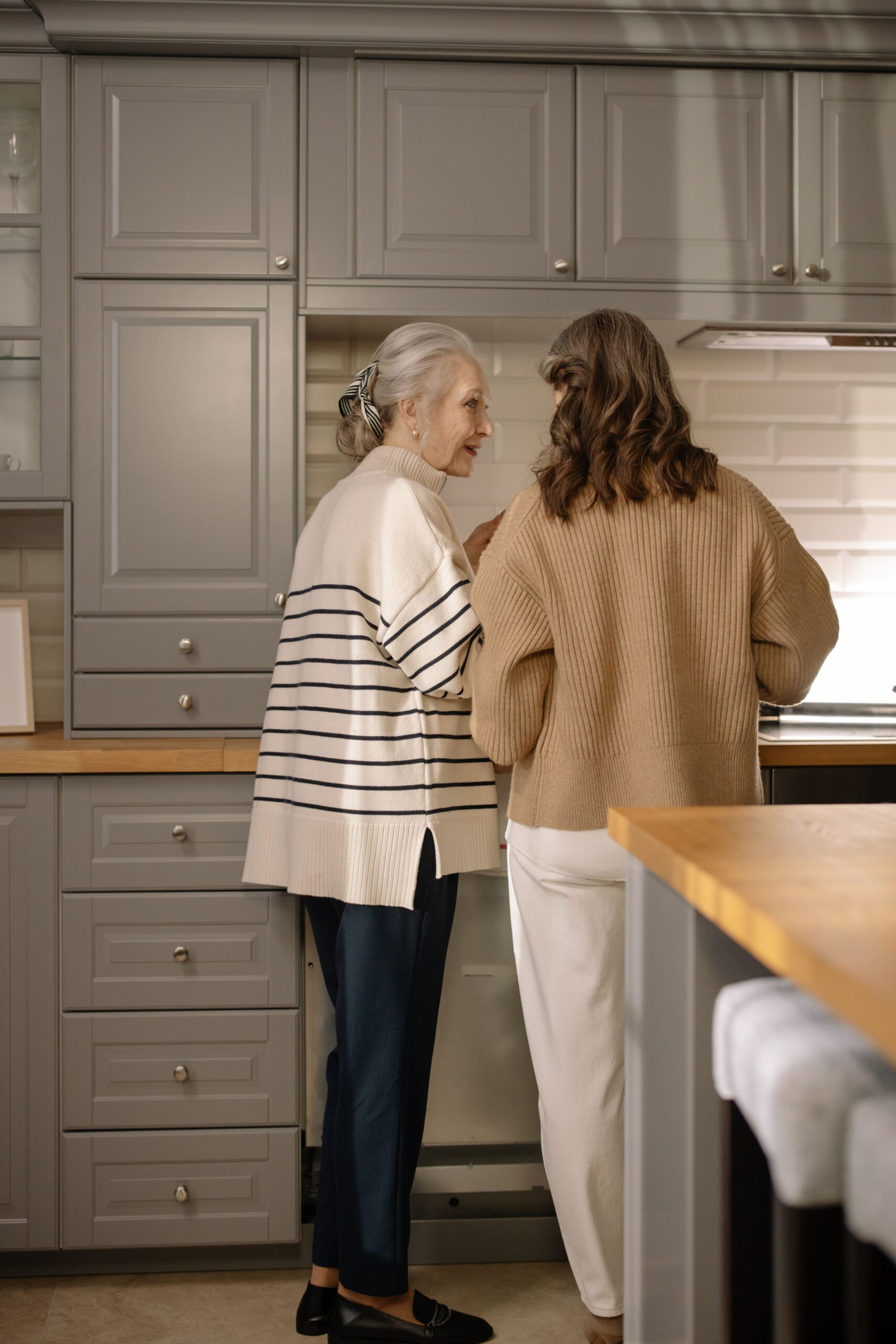 Two senior women sharing a warm moment in a home kitchen